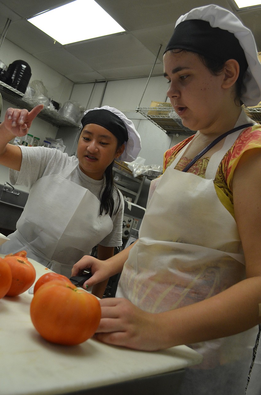 Jennifer Woodford, 14, and Karenna DiPillo, 12, figure out how to properly cut a tomato.