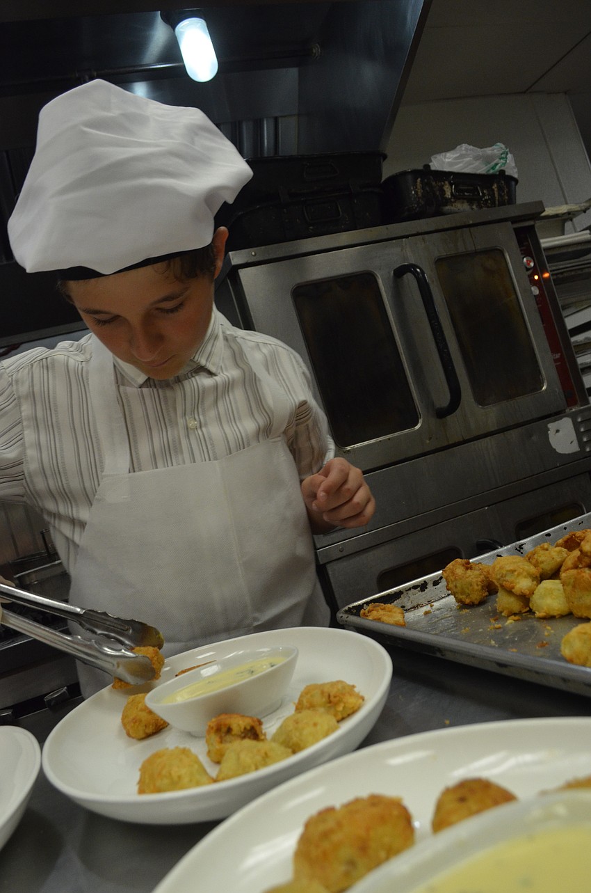 Nicolas Duverneuil, 13, puts artichokes esther-style onto plates.