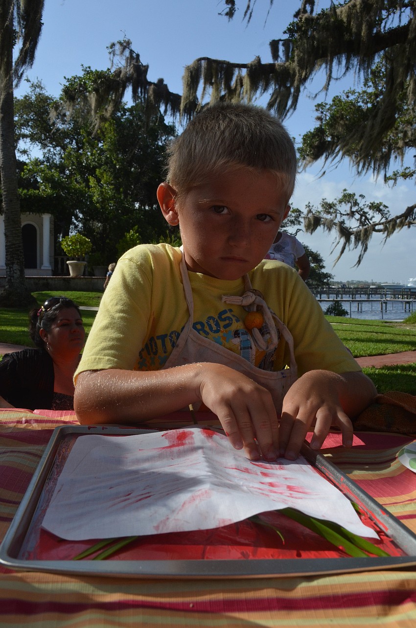 Sean McDonnell, 6, presses down leaves he found on his nature tour for the printmaking project.