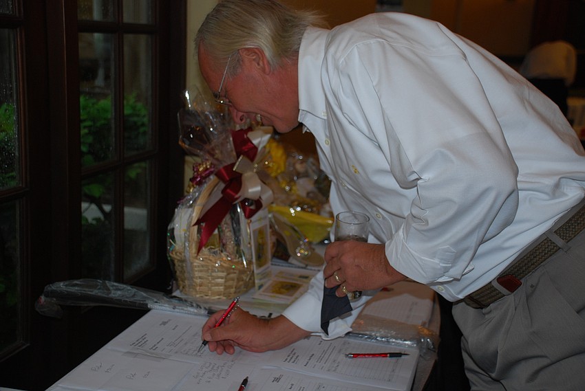 Russ Townsend places a bid on a wine basket in the silent auction