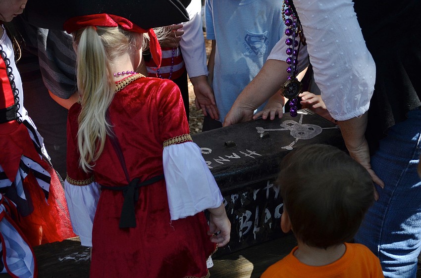 The children crowd around the treasure chest they found during the treasure hunt.