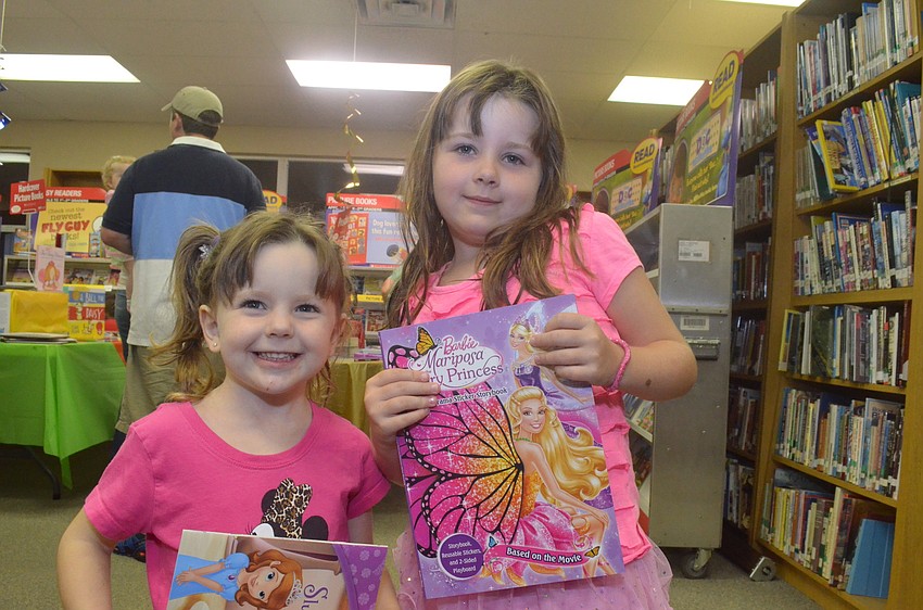 Sisters Faith Rommett, 3, and Ava, 5, look through books they can later read.