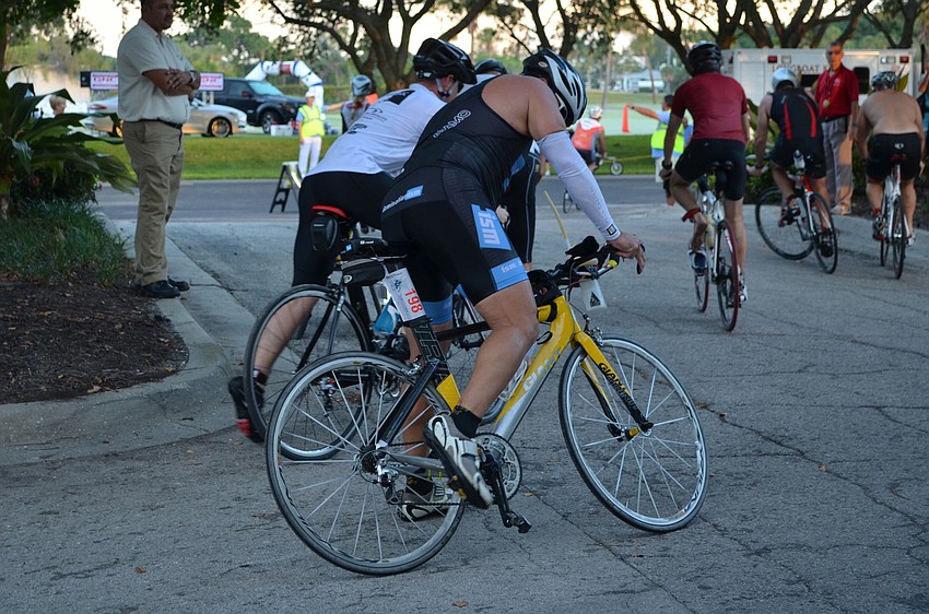 After completing the running portion of the triathlon, cyclists quickly mount on their bikes and continue racing.