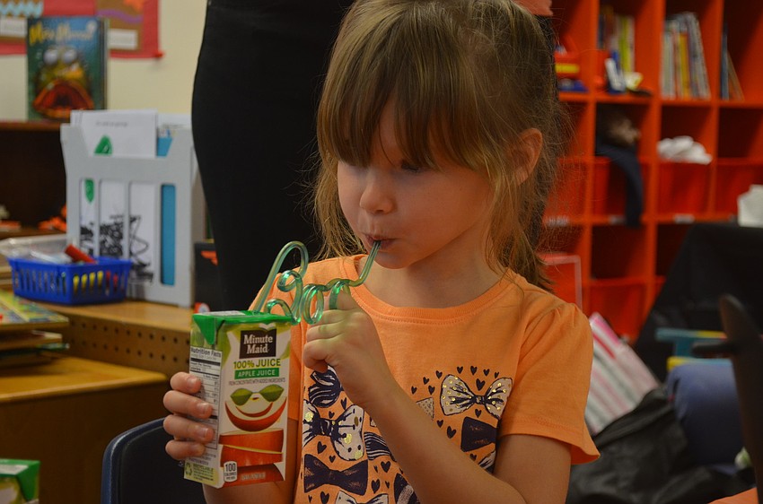 Sarenna Borda sips her apple juice through a festive crazy straw
