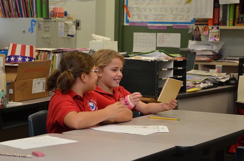 Olivia Williamson and Finley Linehan look at the visuals Spinella passed around the classroom during his presentation.