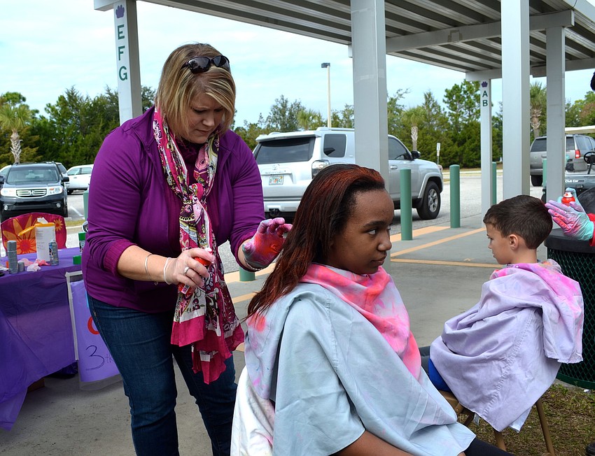 Second-grade teacher Carolyn Winget puts temporary color spray in 11-year-old Jenna Viard's hair.