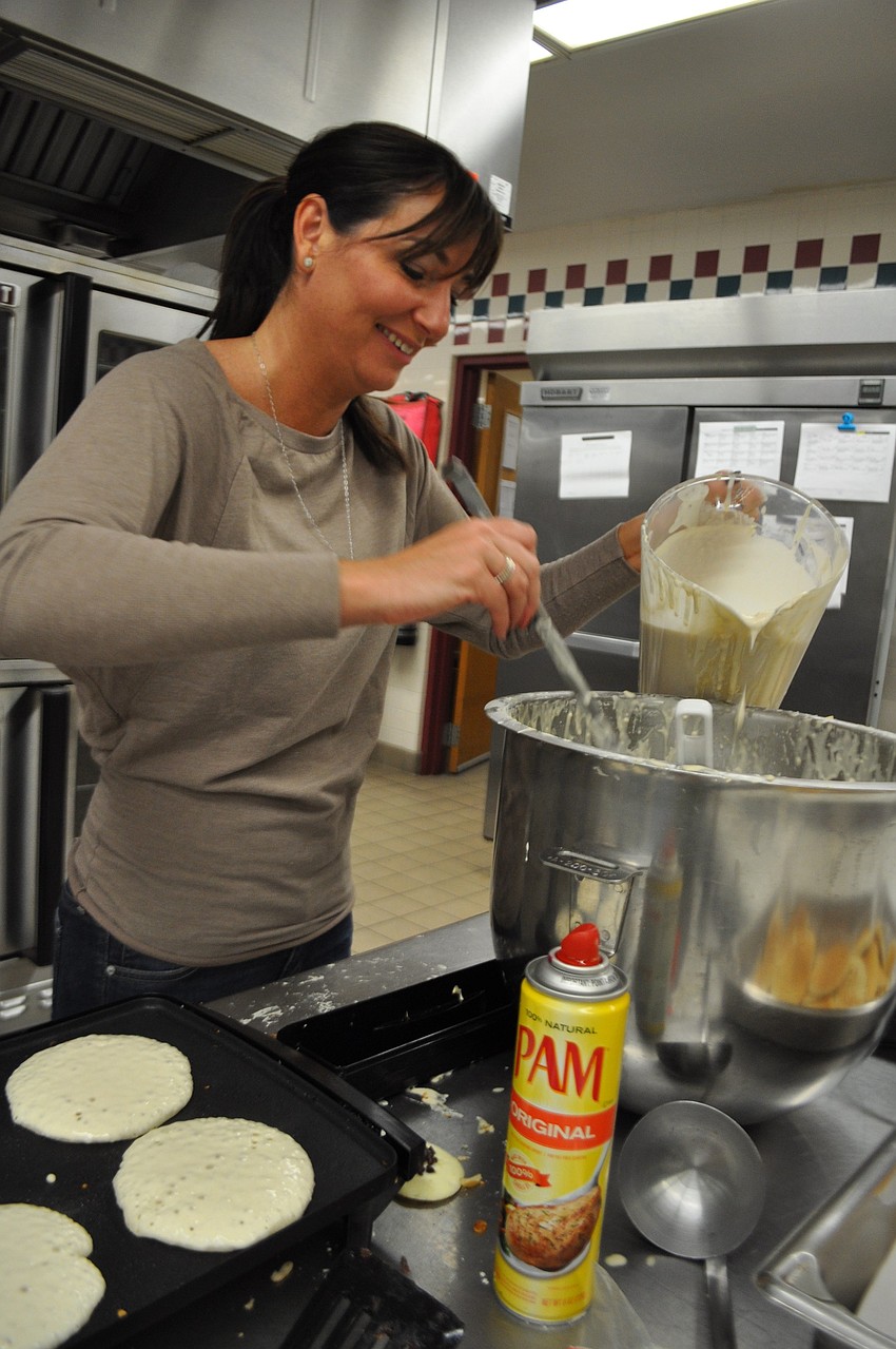 arent volunteer Tara Simmons spoons pancake batter onto the griddle.