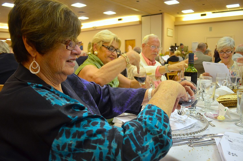 Miriam Goldfarb, Lydia Bohn and Jay Berman take out drops of wine with their little finger to signify â€œthe lessening of our cup of joy when we drip ten drops in remembrance of the plagues that afflicted the Egyptians.â€