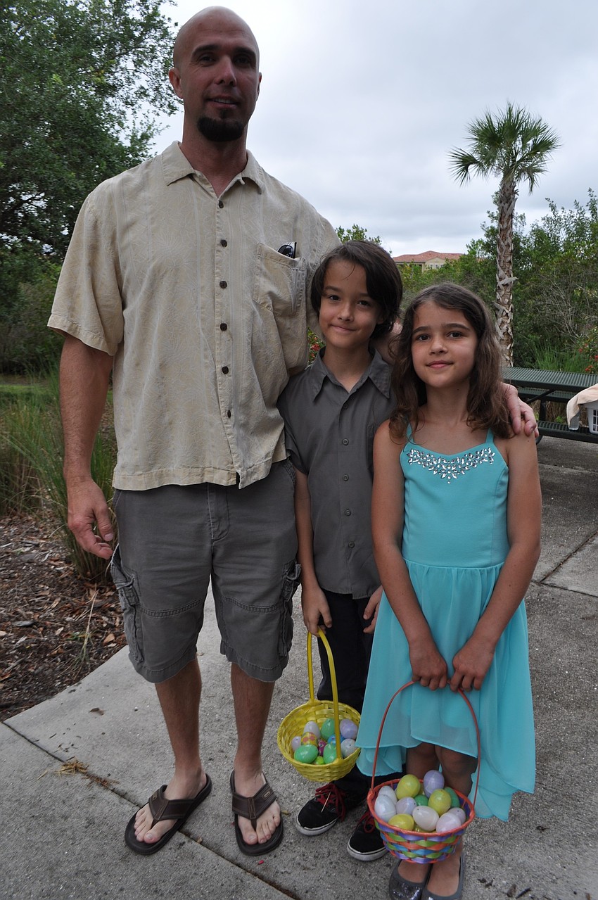 Tom Bolton helps his children, Zane and Kyla, find eggs.