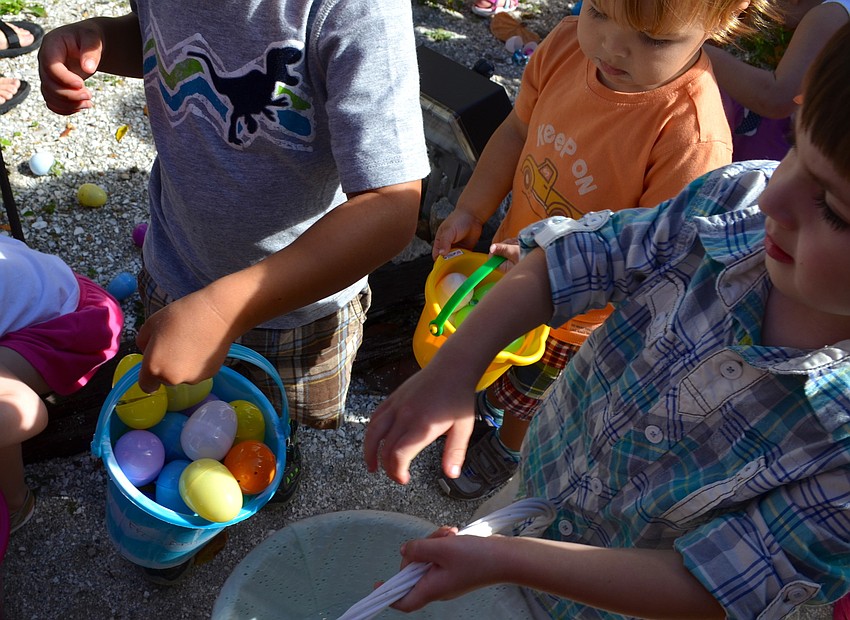 The children fill their buckets and baskets the colorful eggs.