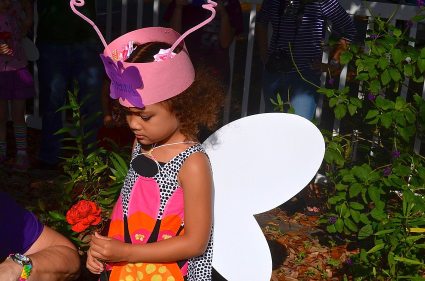 Sienna McQueen watches Carol Beatty pull a butterfly from its container.