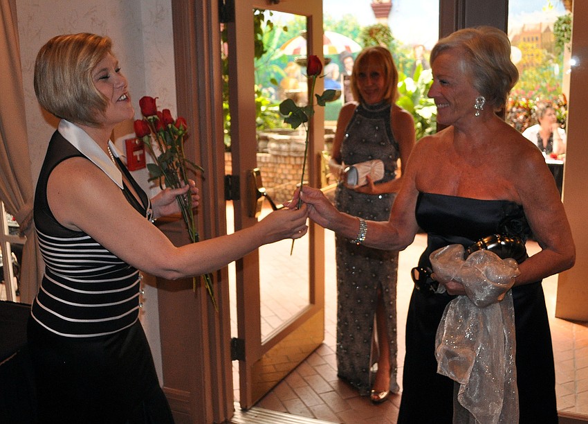 Karen Koblenz hands Dlorah Hayden a rose as she walks in the door for the volunteer luncheon.