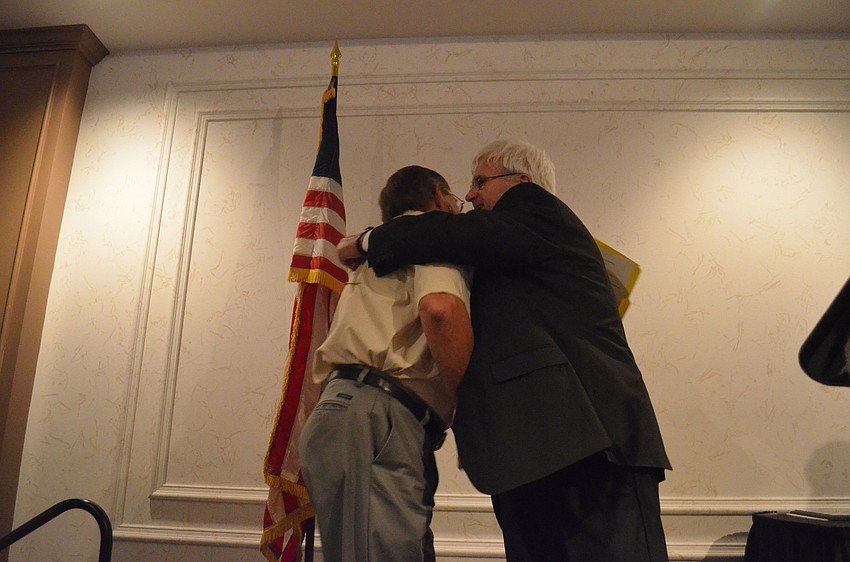 President of the Sarasota County Veterans Commission Andy Hooker embraces veteran Rick Rogala as he accepts his award,
