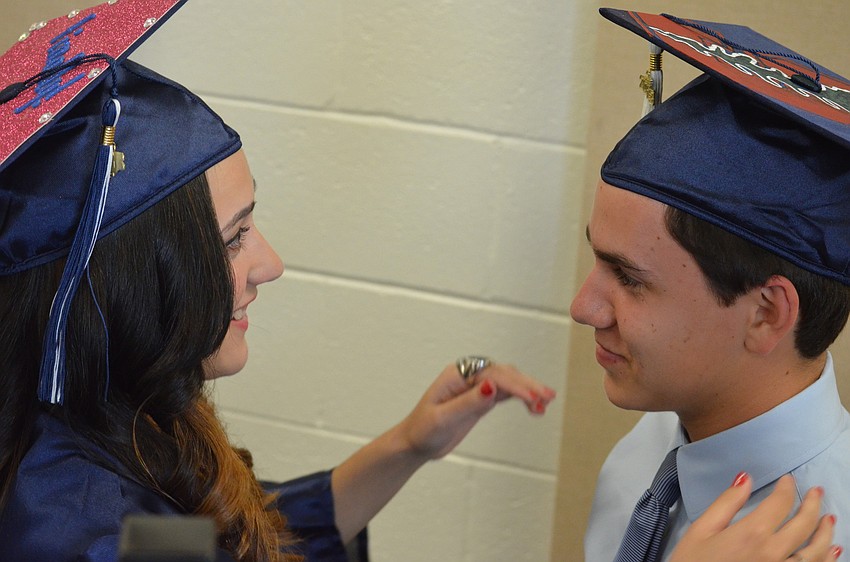 Gabriella Alvarez adjusts valedictorian Kevin Moodyâ€™s cap. Alvarez will attend the University of Florida and plans to study dermatology. Moody will attend Stanford University and plans to study engineering.