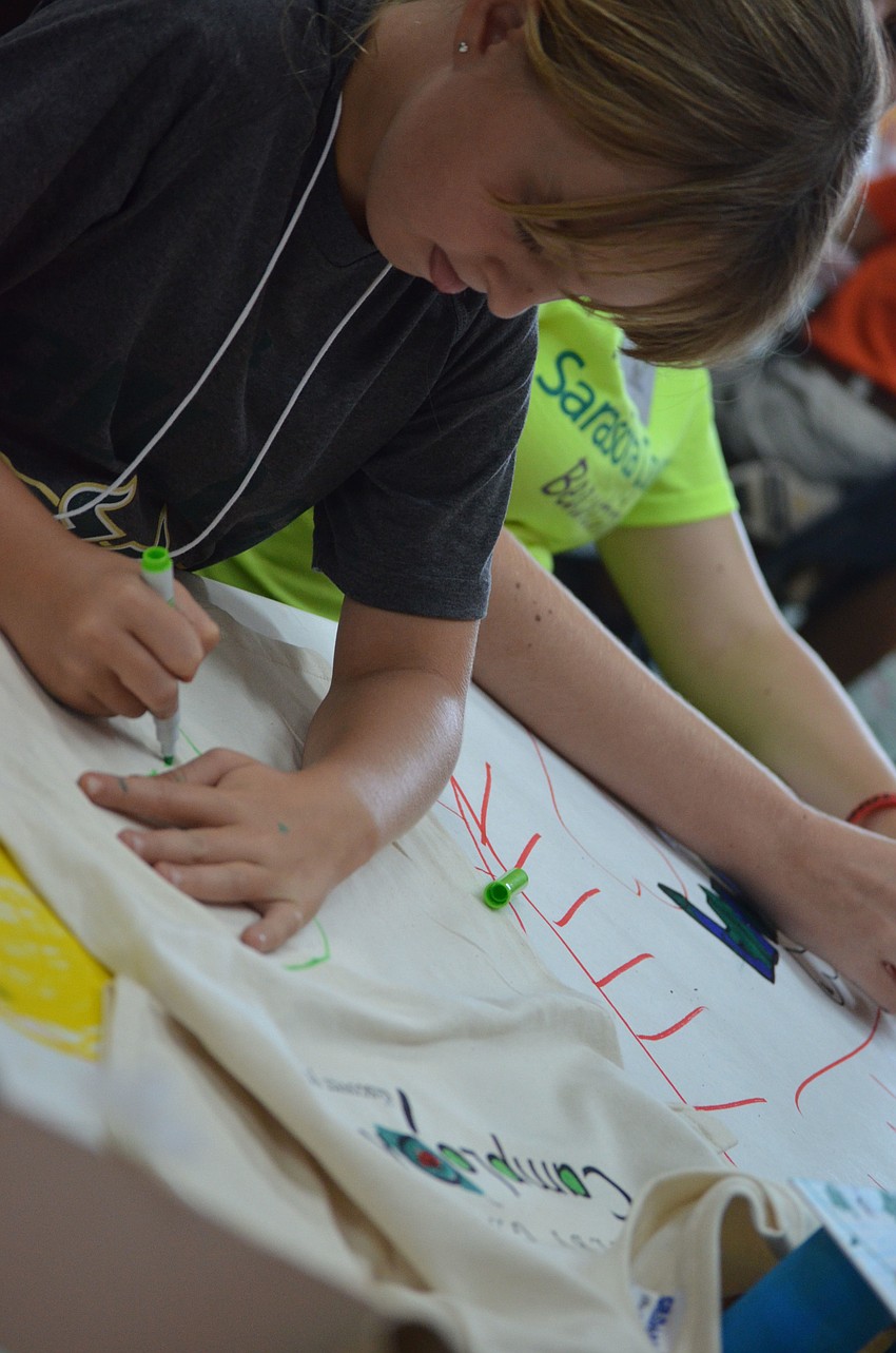 Hannah Farley, 8, colors her Camp Lookout t-shirt with fabric markers.