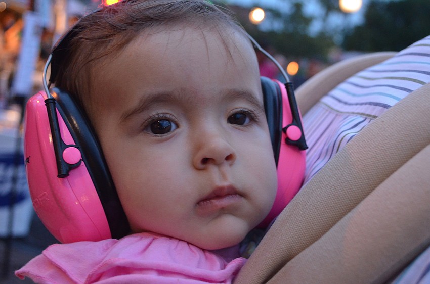 Erin Lopez, 9 months, wears protectors over her ears to protect them from all of the noise.