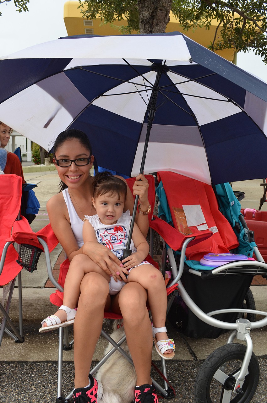 Monika Burke and her daughter Penny, 2, hide under an umbrella during the parade.