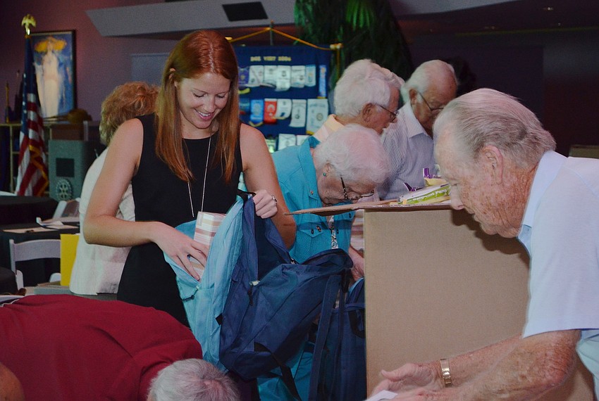 Christina Rogers-Hehr and other volunteers fill the backpacks with school supplies.