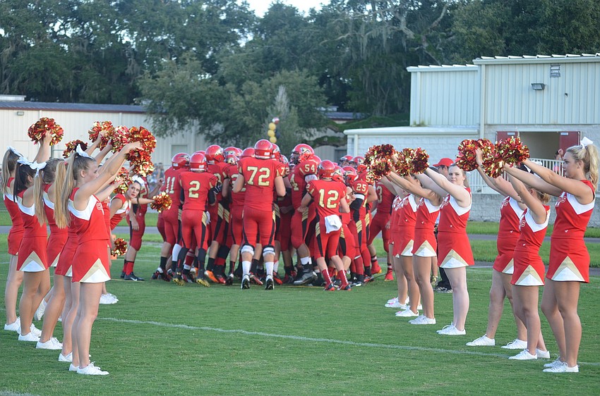 Cheerleaders welcome the football players onto the field at the opening of the game.