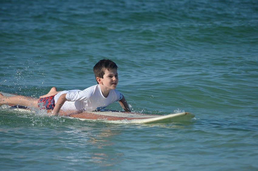 Harrison Troyan, 6, paddles on the surfboard.