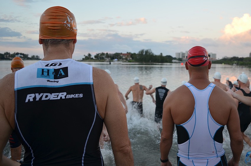 Athletes watch as fellow competitors begin swimming.