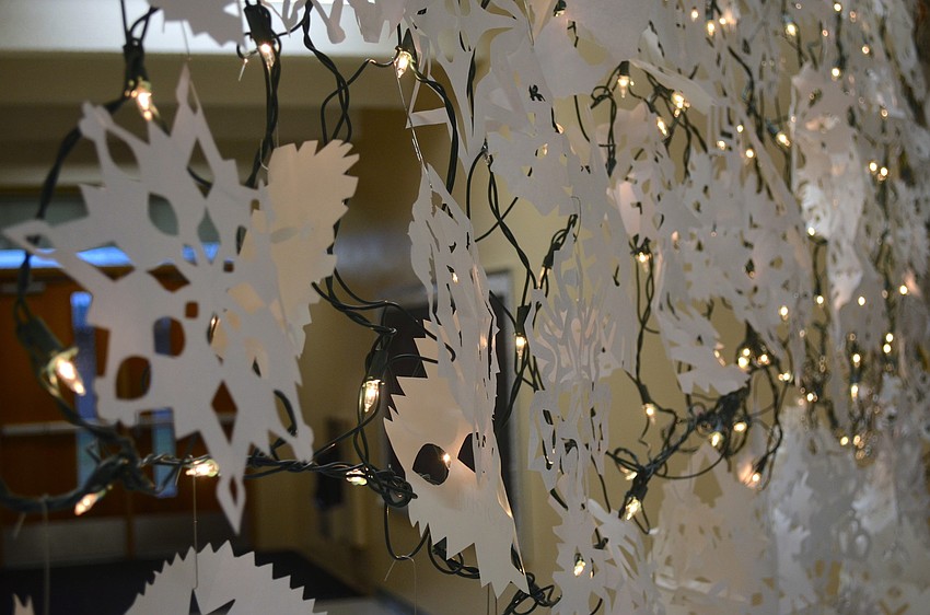 Students crafted paper snowflakes illuminated by white lights.