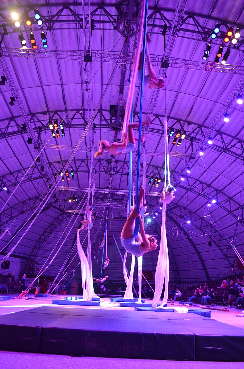Aerial Silk Artists stack in a row of three on either end of the arena with single silk performers filling the space in between.