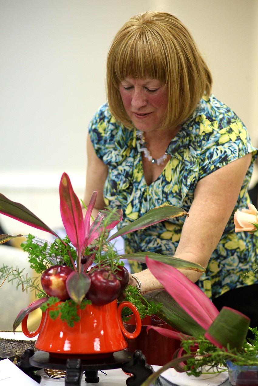 Sherry Linhart arranges a centerpiece with apples and cranberries as accents.