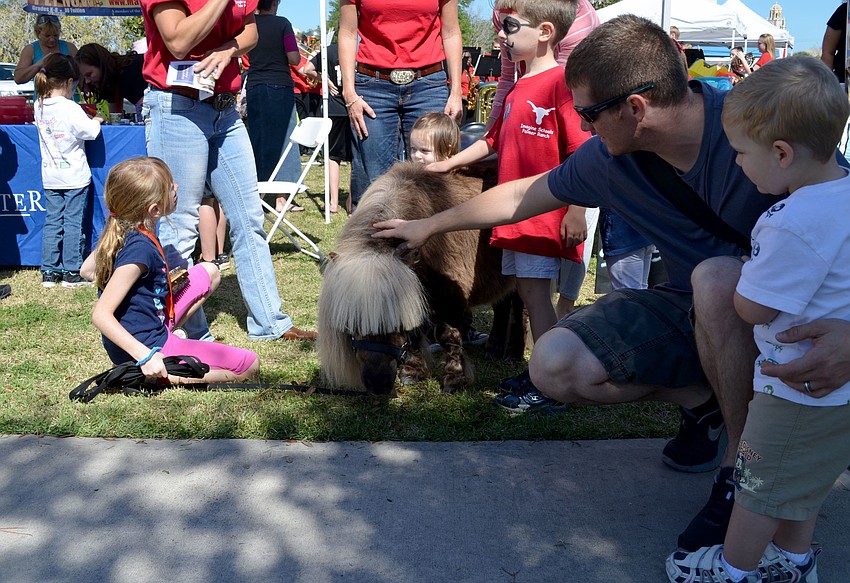 Nathan Vogan and his son, Vincent, pet a miniature horse.