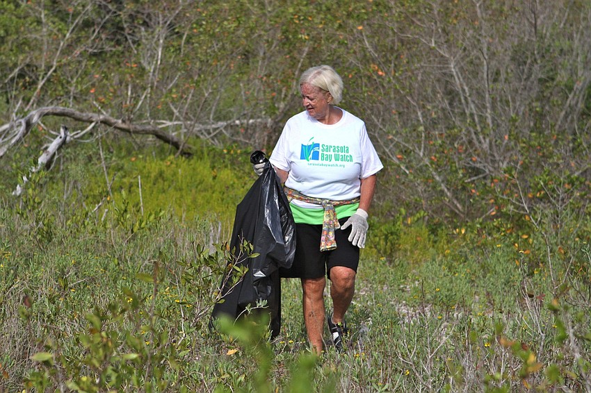 Betsy Falls walks around the island with her garbage bag looking for trash.