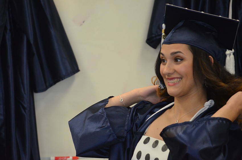 Gabriella Alvarez puts on her cap and gown in the Arts Center before graduation.