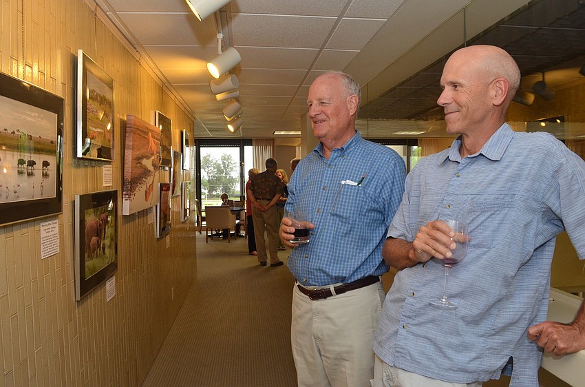 Members of the Sarasota Audubon Society John Ginaven and Stu Wilson look at Lou Newmanâ€™s photos of wildlife in Tanzania.