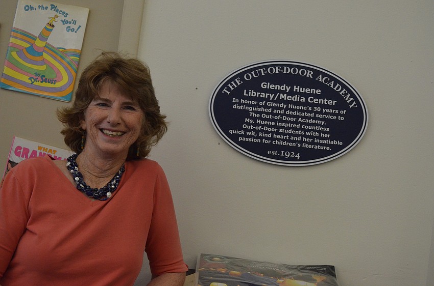 Glendy Huene stands in front of a plaque with her name inside the library.