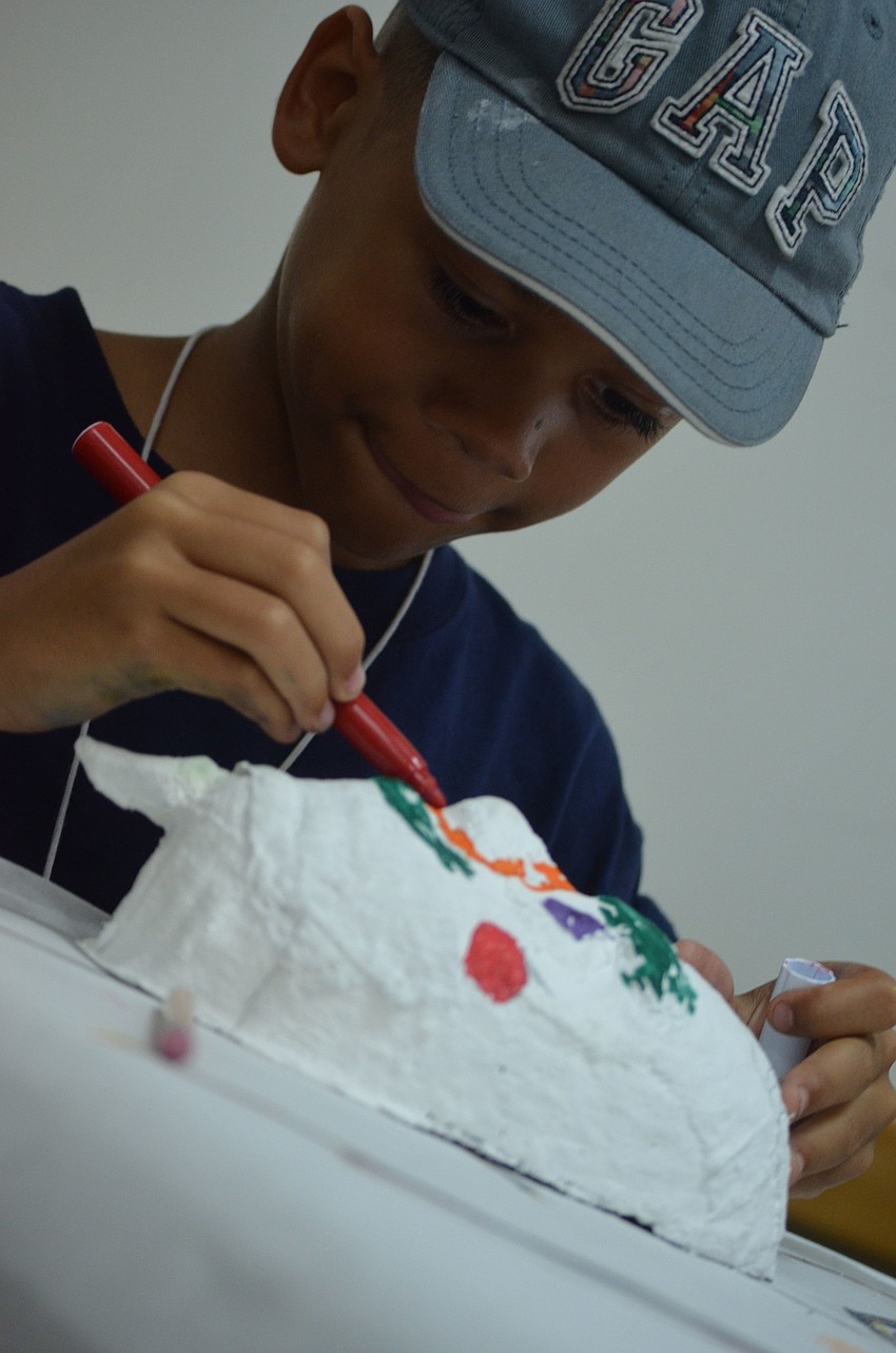 Jeremiah Fisher, 8, focuses on coloring his renaissance inspired mask.