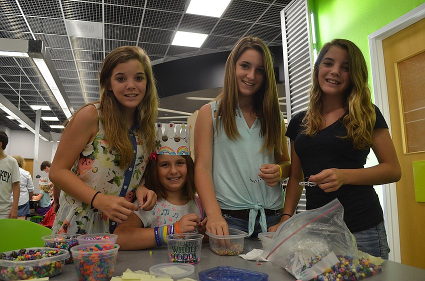 Heather Haley, Dahlia Arslanagic, Yasmeen Arslanagic and Meagan Haley make a bracelet at a craft table.