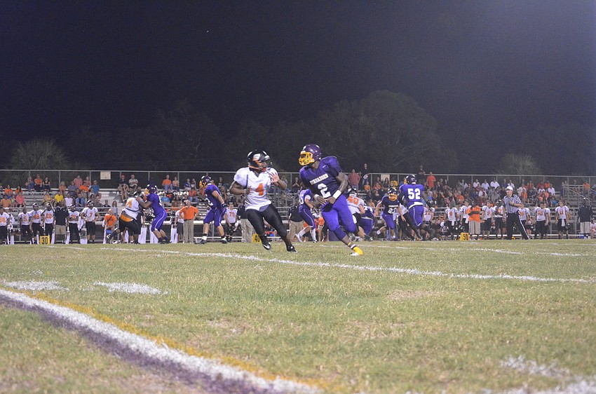 Sarasota High School football player Dominique Austin and Booker High School football player Marlon Mack run down the field.
