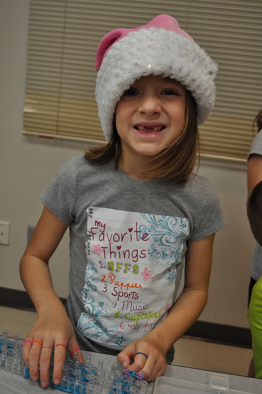 Anna Weidel, 7, weaves a rainbow bracelet.