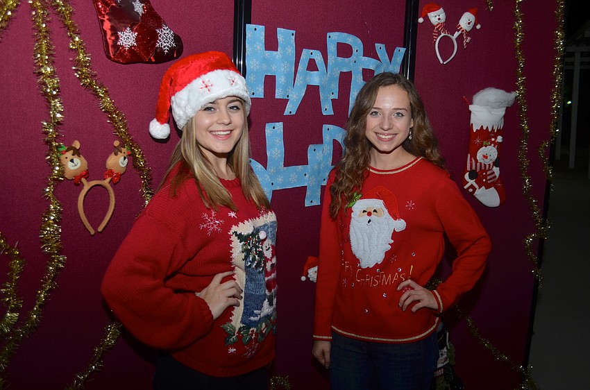 Emma Slotabec, 16, and Katie Cafiero, 17, find a spot near a Happy Holidays sign.