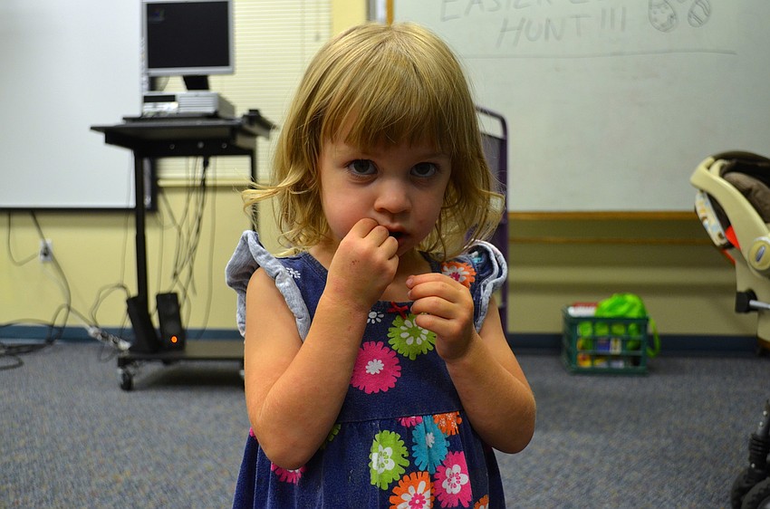 Isabella Carlson, 2, snacks on chocolate she found during the hunt.