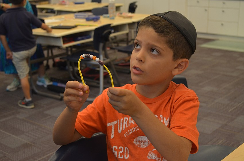 Tyler Ruben takes a break from stuffing his doll to make a bead bracelet.