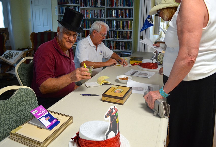 Greg Fiore enjoys a mint julep while attendees pick their horses.