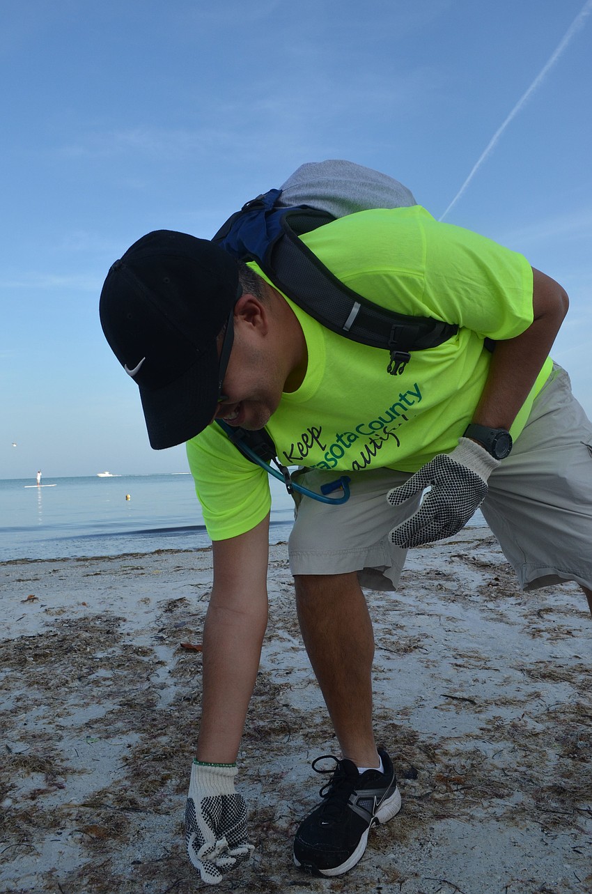 Paul Janis picks up trash on the beach.