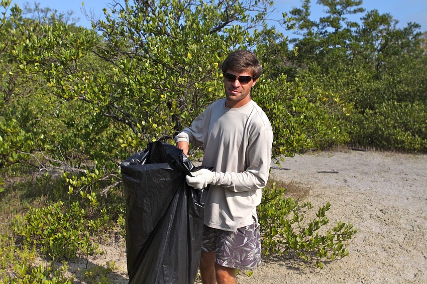 John Gricius helps Kathy Gricius fill up a large, garbage bag during the Sister Keys Clean Up.