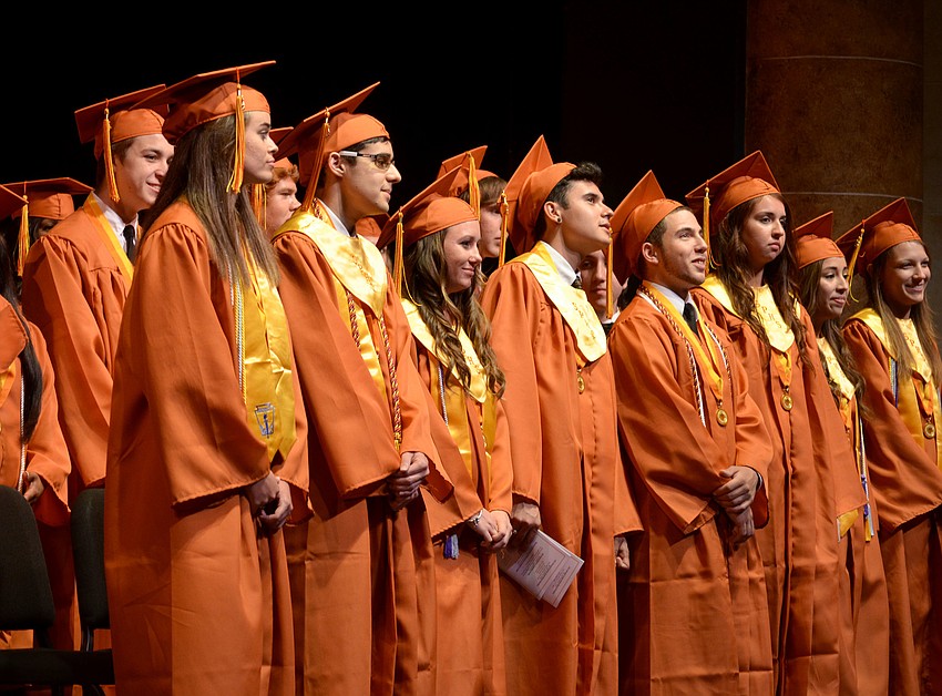 Students stand to receive their diplomas.