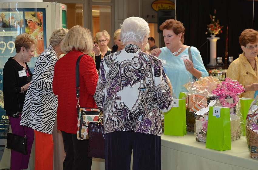 Guests at the fashion show luncheon browse the table of raffle items.