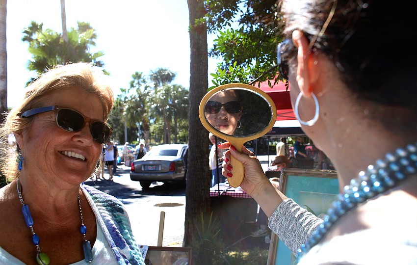 Ann Segal laughs as her friend, Deborah Simon, looks at her recently purchased necklace in a mirror.