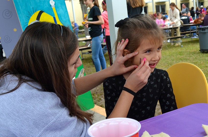 Amy Alvarez, 17, colors a butterfly onto 5-year-old Emma Mandzik's face.