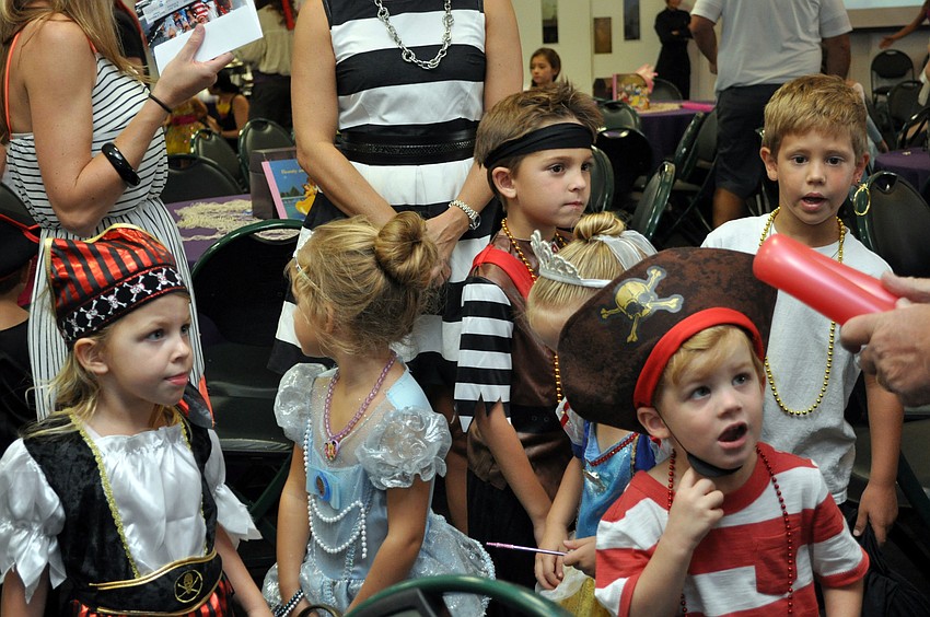 A few princesses and pirates wait in line for a balloon.