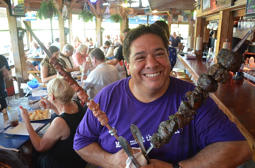 Chef Rafael Manzano holding Brazilian steak and sausage at Phillippi Creek Village Restaurant