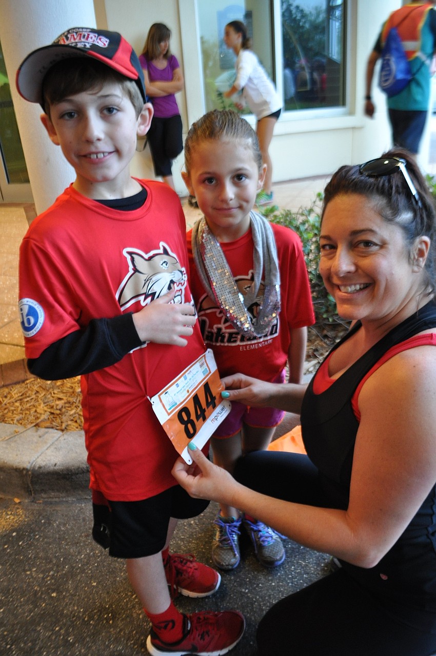 Stephanie Dennis, right, helps her son, Bobby, and daughter, Sophie, put on their race bibs.